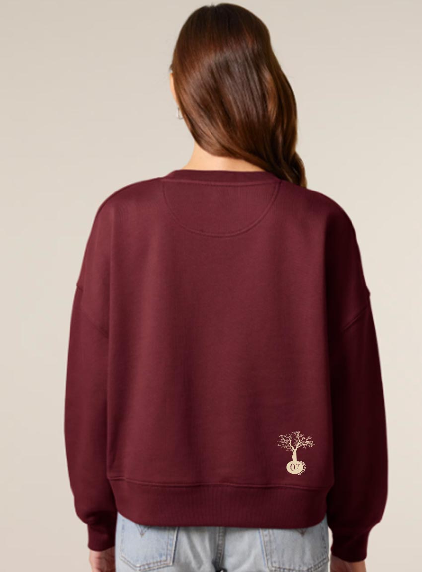 Sweat femme en coton biologique de couleur bordeau avec une sérigraphie beige en bas dans le dos représentant un arbre sur une planète.