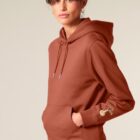 Sweat pour femme et homme en coton biologique de couleur terracotta avec un dessin sur la manche d'un arbre et d'une planète, la sérigraphie est de couleur beige.