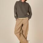 Sweat bio femme avec capuche de couleur mocha avec le dessin de la marque sur la manche représentant un homme qui grimpe sur un arbre au dessus de la planète. La couleur de sérigraphie est beige.