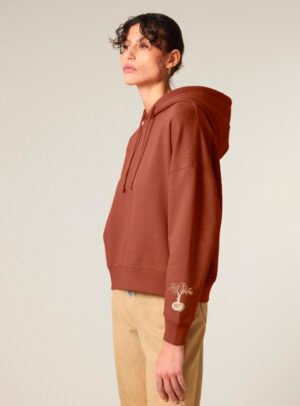 Sweat bio femme avec capuche de couleur terracotta avec le dessin de la marque sur la manche représentant un homme qui grimpe sur un arbre au dessus de la planète. La couleur de sérigraphie est beige.