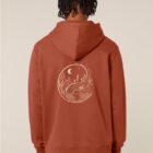 Sweat pour homme et femme en coton biologique de couleur terracotta avec un dessin dans le dos représentant le yin et yang de la nature, d'un coté les montagnes et de l'autre la plage la sérigraphie est de couleur beige.