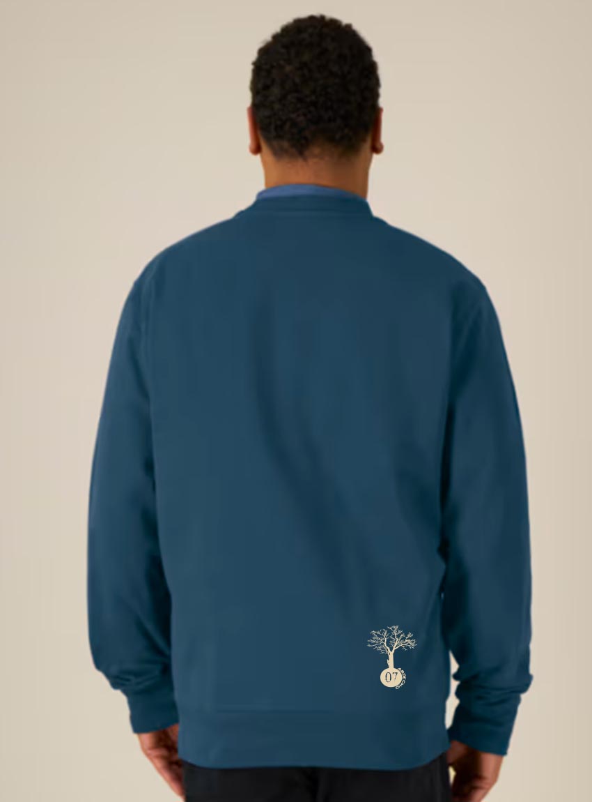 Sweat homme en coton biologique de couleur denim avec une sérigraphie beige en bas dans le dos représentant un arbre sur une planète.