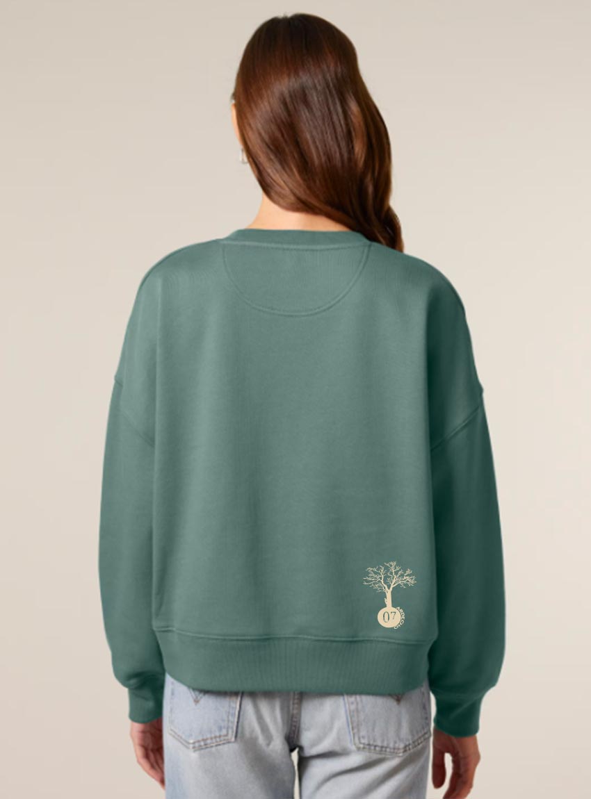 Sweat femme en coton biologique de couleur vert jade avec une sérigraphie beige en bas dans le dos représentant un arbre sur une planète.