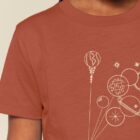 Tshirt enfant manche courte en coton biologique de couleur terracotta avec un dessin représentant des planètes en forme de ballons tenu par le petit prince et son renard. La couleur de sérigraphie est beige.