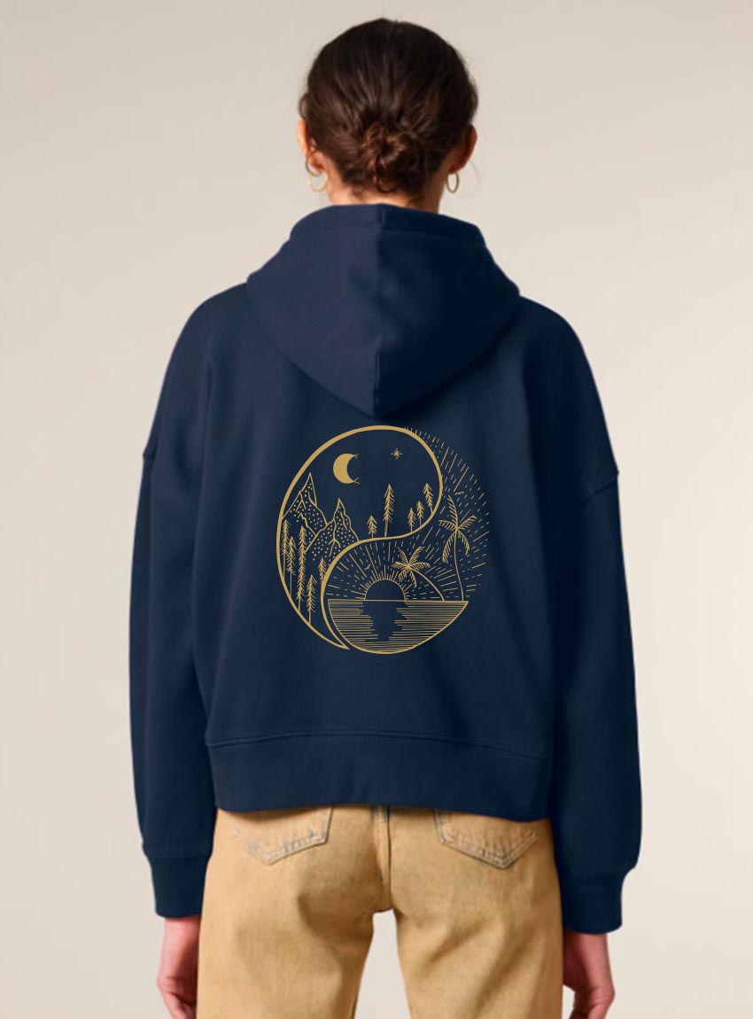 Veste zippé pour femme en coton biologique de couleur bleu marine avec un dessin dans le dos représentant le yin et yang de la nature, d'un coté les montagnes et de l'autre la plage la sérigraphie est de couleur doré.