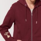 Veste sweat pour femme et homme en coton biologique de couleur bordeau avec un dessin sur la manche d'un arbre et d'une planète, la sérigraphie est de couleur beige.