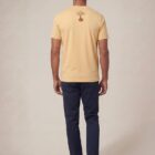 Tshirt homme manche courte en coton biologique de couleur jaune blé vue de dos avec le dessin de la marque entre les épaules et la sérigraphie est de couleur marron.