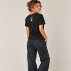 T-shirt femme manche courte en coton biologique de couleur noir vue de dos avec le dessin de la marque entre les épaules et la sérigraphie est de couleur argenté.
