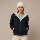 Photo de présentation du sweat à capuche zippé unisexe Polaire, en coton biologique, coloris noir, porté par un modèle femme. Collection Ardecho 07. Zoom sur la polaire.