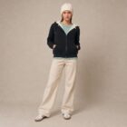 Photo de présentation du sweat à capuche zippé unisexe Polaire, en coton biologique, coloris noir, porté par un modèle femme. Collection Ardecho 07.
