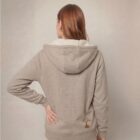 Photo de présentation du sweat à capuche unisexe Polaire, en coton biologique, coloris crème chiné, porté par un modèle femme. Collection Ardecho 07. Zoom sur la polaire de dos avec le dessin de la marque en bas à droite représentant un arbre sur la planète et un homme qui grimpe à l'arbre, la sérigraphie est de couleur marron.