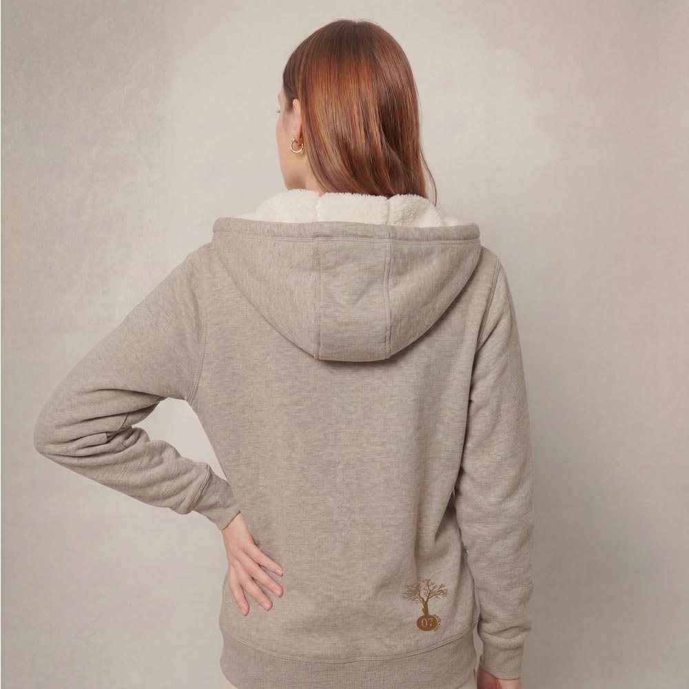 Photo de présentation du sweat à capuche unisexe Polaire, en coton biologique, coloris crème chiné, porté par un modèle femme. Collection Ardecho 07. Zoom sur la polaire de dos avec le dessin de la marque en bas à droite représentant un arbre sur la planète et un homme qui grimpe à l'arbre, la sérigraphie est de couleur marron.