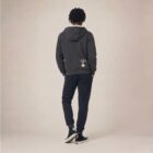 Photo de présentation du sweat à capuche unisexe Polaire, en coton biologique, coloris anthracite, porté par un modèle homme. Collection Ardecho 07. Vue de dos avec le dessin de la marque en bas à droite, représentant un arbre sur la planète et un homme qui grimpe à l'arbre, la sérigraphie est de couleur beige.