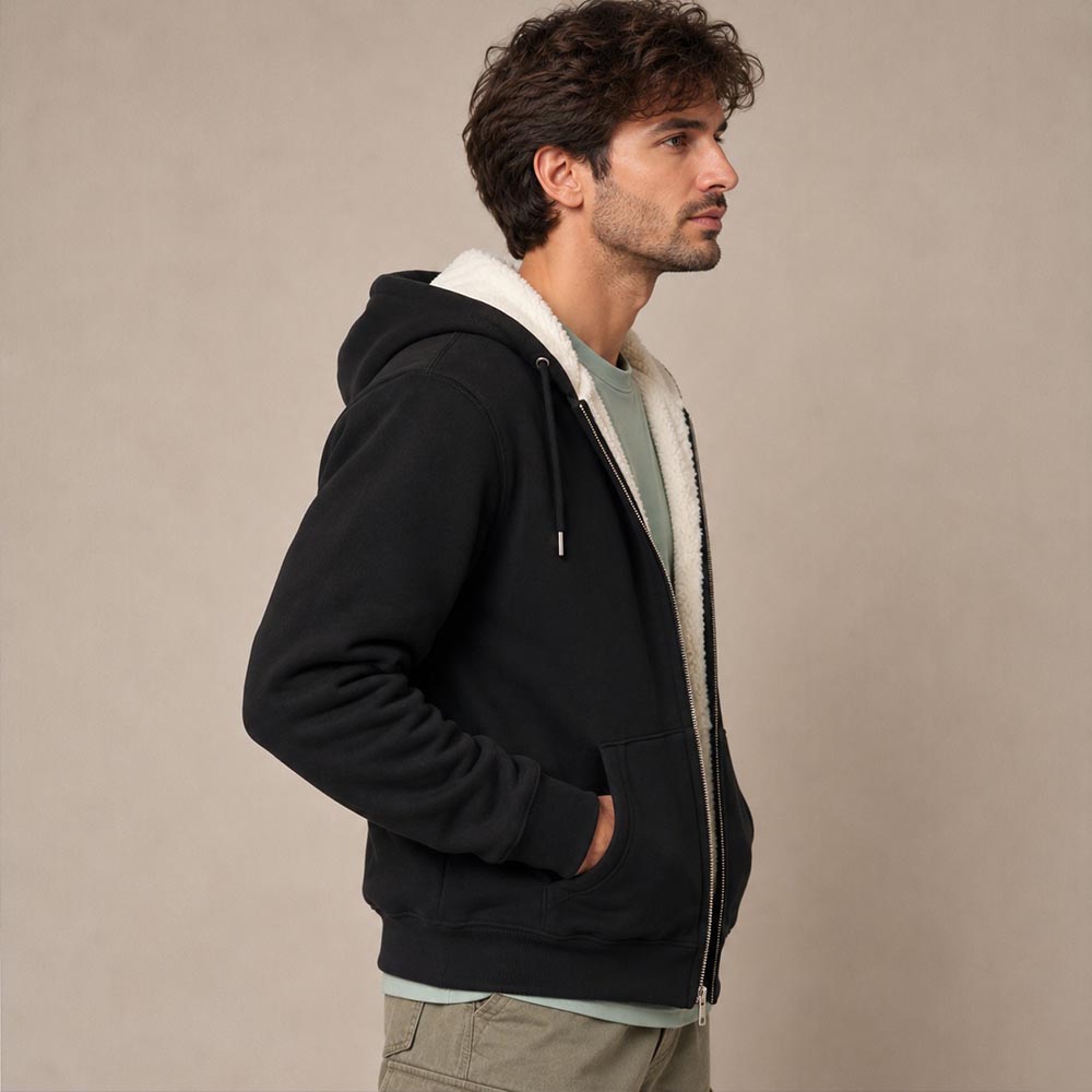 Photo de présentation du sweat à capuche zippé unisexe Polaire, en coton biologique, coloris noir, porté par un modèle homme. Collection Ardecho 07. Zoom sur la polaire vue de coté.