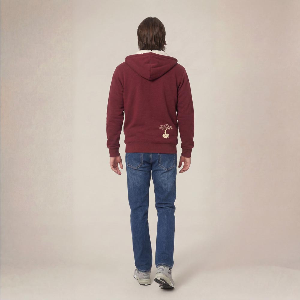 Photo de présentation du sweat à capuche unisexe Polaire, en coton biologique, coloris bordeaux, porté par un modèle homme. Collection Ardecho 07. Vue de dos avec le dessin de la marque en bas à droite, représentant un arbre sur la planète et un homme qui grimpe à l'arbre, la sérigraphie est de couleur beige.