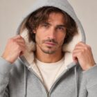 Photo de présentation du sweat à capuche zippé unisexe Polaire, en coton biologique, coloris gris chiné, porté par un modèle homme. Collection Ardecho 07. Zoom sur la capuche et le visage du mannequin.