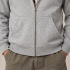Photo de présentation du sweat à capuche zippé unisexe Polaire, en coton biologique, coloris gris chiné, porté par un modèle homme. Collection Ardecho 07. Zoom sur la veste fermée.