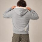 Photo de présentation du sweat à capuche zippé unisexe Polaire, en coton biologique, coloris gris chiné, porté par un modèle homme. Collection Ardecho 07. Zoom sur la polaire de dos avec le dessin de la marque en bas à droite, représentant un arbre sur la planète et un homme qui grimpe à l'arbre, la sérigraphie est de couleur beige.