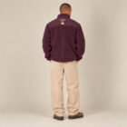 Polaire polyester recyclé homme couleur aubergine avec le dessin de la marque entre les épaules représentant un arbre sur la planète et un homme qui grimpe à l'arbre, sérigraphie de couleur beige. Vue de dos.