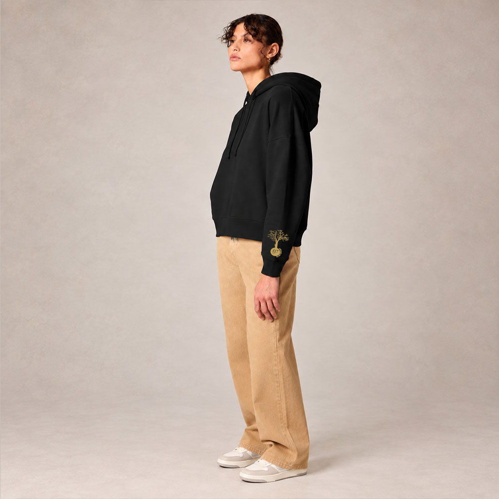 Sweat avec capuche femme en coton biologique de couleur noir avec le dessin de la marque sur la manche représentant un arbre sur une planète et une personne qui monte dans l'arbre. Sérigraphie doré, Vue de coté.