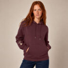 Sweat femme à capuche en coton biologique couleur aubergine avec le dessin du logo de la marque qui représente un arbre sur une planète et une personne qui monte à l'arbre. Poche kangourou, le dessin est sur la manche de couleur beige. Zoom sur le sweat.