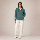Sweat avec capuche et fermeture éclaire pour femme en coton biologique de couleur vert jade. Le logo de la marque est imprimé en beige sur la manche, un arbre sur une planète et un homme qui monte à l'arbre.