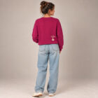 Sweat femme en coton biologique de couleur framboise avec le dessin de la marque dans le dos en bas à droite représentant un arbre sur une planète et un homme qui grimpe à l'arbre. La sérigraphie est de couleur beige. Vue de dos.