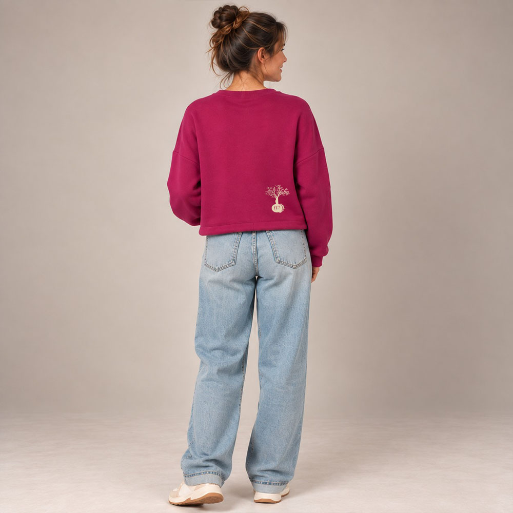 Sweat femme en coton biologique de couleur framboise avec le dessin de la marque dans le dos en bas à droite représentant un arbre sur une planète et un homme qui grimpe à l'arbre. La sérigraphie est de couleur beige. Vue de dos.