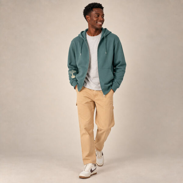 Sweat avec capuche et fermeture éclaire pour homme en coton biologique de couleur vert jade. Le logo de la marque est imprimé en beige sur la manche, un arbre sur une planète et un homme qui monte à l'arbre.