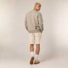 Sweat homme en coton biologique de couleur greige avec le dessin de la marque, en bas dans le dos représentant un arbre sur une planète et un homme qui grimpe à l'arbre, la sérigraphie est de couleur noir.