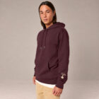 Sweat homme à capuche en coton biologique couleur aubergine avec le dessin du logo de la marque qui représente un arbre sur une planète et une personne qui monte à l'arbre. Poche kangourou, le dessin est sur la manche de couleur beige. Zoom sur le sweat.