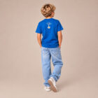 T-shirt enfant manche courte en coton biologique de couleur bleu roi vue de dos avec le dessin de la marque entre les épaules et la sérigraphie est de couleur beige.