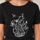 T-shirt femme à manche courte en coton biologique couleur noir avec un dessin de bouquet de fleurs en forme allongée. Avec une inscription ' La clef des champs', la sérigraphie est de couleur argenté. Zoom sur le t-shirt.