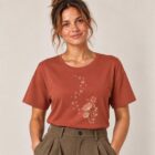 T-shirt femme à manche courte en coton biologique couleur terracotta avec un dessin d'abeilles s'envolant d'un pissenlit . Avec une inscription ' Bee la vie ' la sérigraphie est de couleur beige. Zoom sur le t-shirt.